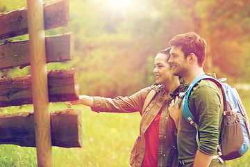 Image showing smiling couple at signpost with backpacks hiking