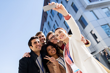 Image showing happy people with conference badges taking selfie