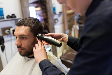 Image showing man and barber with trimmer cutting hair at salon