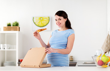 Image showing happy pregnant woman eating pizza at home kitchen