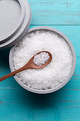 Image showing Sea salt in an stone bowl with small wooden spoon on a blue wooden table