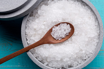 Image showing Sea salt in an stone bowl with small wooden spoon on a blue wooden table