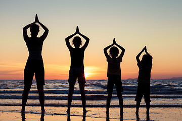 Image showing Mother and children playing on the beach at the sunset time.