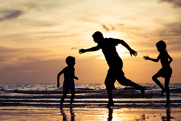 Image showing Father and children playing on the beach at the sunset time.