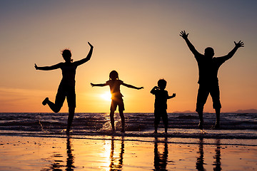 Image showing Silhouette of happy family who playing on the beach at the sunse