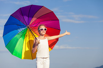 Image showing Ten girl with umbrella standing on the beach