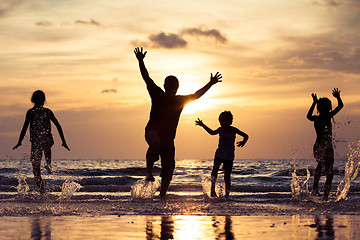 Image showing Father and children playing on the beach at the sunset time.