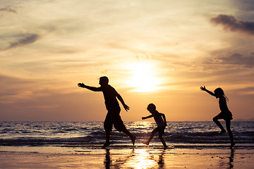 Image showing Father and children playing on the beach at the sunset time.