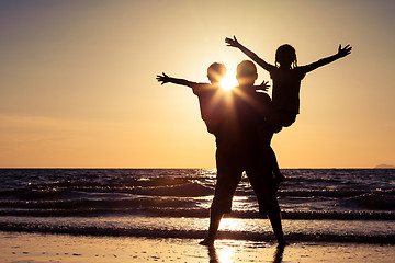 Image showing Father and children playing on the beach at the sunset time.