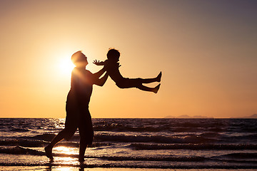 Image showing Father and son playing on the beach at the sunset time.