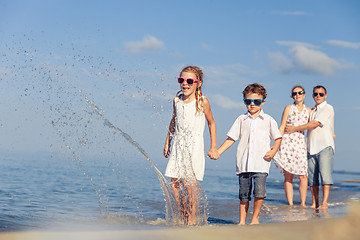 Image showing Happy family walking on the beach at the day time.