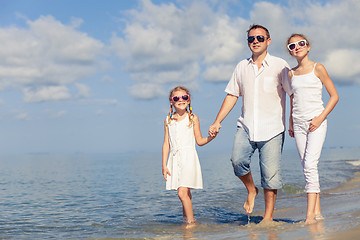 Image showing Father and children sitting on the beach at the day time.