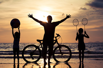 Image showing Father and children playing on the beach at the sunset time.