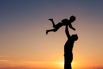 Image showing Father and son playing on the beach at the sunset time.