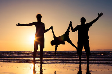 Image showing Silhouette of happy family who playing on the beach at the sunse