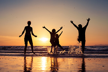 Image showing Silhouette of happy family who playing on the beach at the sunse