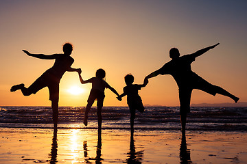 Image showing Silhouette of happy family who playing on the beach at the sunse