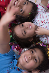 Image showing kids  blowing confetti while lying on the floor