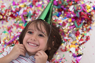 Image showing kid blowing confetti while lying on the floor