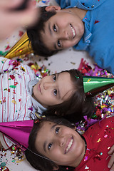 Image showing kids  blowing confetti while lying on the floor