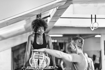 Image showing black woman doing parallel bars Exercise with trainer