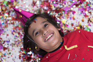 Image showing kid blowing confetti while lying on the floor