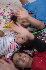 Image showing kids  blowing confetti while lying on the floor