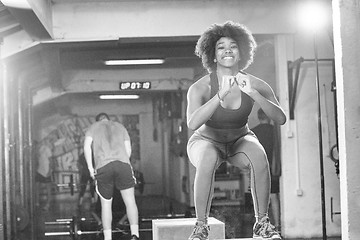 Image showing black female athlete is performing box jumps at gym