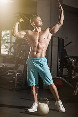 Image showing Muscular bodybuilder guy doing exercises with weight in gym