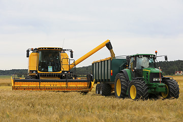 Image showing New Holland Combine Unloads Grain onto Trailer