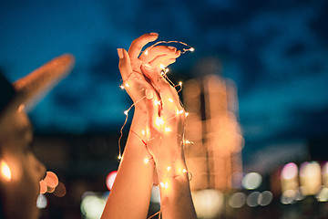 Image showing Beautiful young woman smiling and talking garlands of lights at city