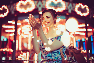 Image showing Beautiful young woman smiling and talking garlands of lights at city