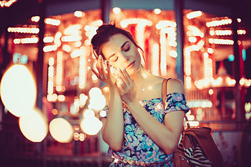 Image showing Beautiful young woman smiling and talking garlands of lights at city