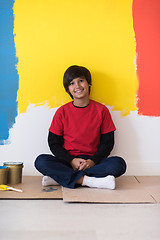 Image showing young boy painter resting after painting the wall