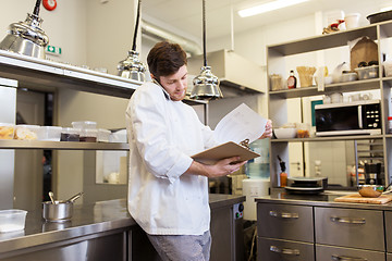 Image showing chef cook calling on smartphone at restaurant kitchen