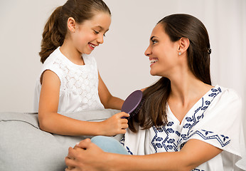 Image showing Lelping mother brushing hair