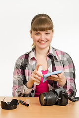 Image showing Girl photographer performs cleaning of the camera body from external contamination