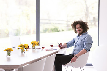 Image showing young man using a mobile phone  at home