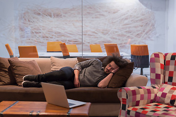 Image showing man sleeping on a sofa  in a creative office