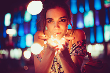 Image showing Beautiful young woman smiling and talking garlands of lights at city