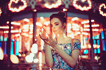 Image showing Beautiful young woman smiling and talking garlands of lights at city