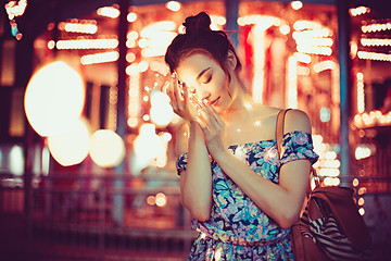 Image showing Beautiful young woman smiling and talking garlands of lights at city