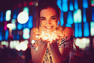 Image showing Beautiful young woman smiling and talking garlands of lights at city