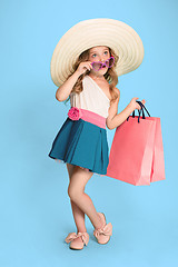 Image showing The cute little caucasian brunette girl in dress holding shopping bags