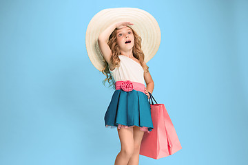 Image showing The cute little caucasian brunette girl in dress holding shopping bags