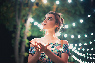 Image showing Beautiful young woman smiling and talking garlands of lights at city