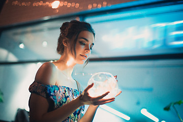 Image showing Beautiful young woman smiling and talking garlands of lights at city