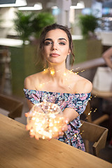 Image showing Beautiful young woman smiling and talking garlands of lights at city