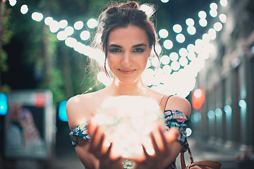 Image showing Beautiful young woman smiling and talking garlands of lights at city