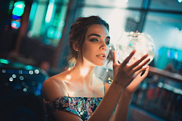 Image showing Beautiful young woman smiling and talking garlands of lights at city